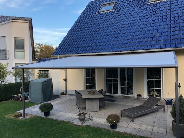 Moderne Terrasse mit Markise, Gartenmöbeln und gepflegtem Außenbereich an Einfamilienhaus.